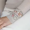 A person's arm wearing multiple Pandora charm bracelets. Anteprima dell’immagine prodotto