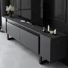 A modern, dark gray TV stand with black legs, holding a television and decorative items. Voir les images du produit