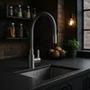 A modern kitchen sink with a flexible faucet, set against a brick wall background with jars of ingredients on a shelf. Produktbild-Vorschau