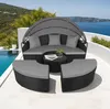 A rattan sun lounger with a canopy and cushions, set on a patio overlooking the sea. Voir les images du produit