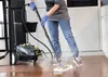 A person is using a steam cleaner on a wooden floor in a kitchen. Voir les images du produit