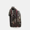 A side view of a multi-compartment handbag with various zippers and decorative charms. Anteprima dell’immagine prodotto