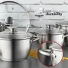 A collection of stainless steel pots with glass lids, set against a brick wall background. Some spaghetti is visible in the foreground. Náhled obrázku produktu