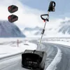 A snow blower with two batteries is shown on a snowy road with mountains in the background. Produktbild-Vorschau