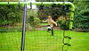 A young boy is playing soccer in a backyard with a rebounder net. Anteprima dell’immagine prodotto