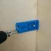 A blue Kreg pocket-hole jig is attached to a piece of wood, with a drill bit inserted into the jig. Voir les images du produit