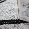 A close-up view of a rug with a geometric pattern and a distressed wooden furniture leg. Anteprima dell’immagine prodotto