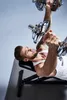 A man is lying on a weight bench and lifting dumbbells. Produktbild-Vorschau