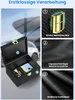 A black box with a gold clasp, containing car keys and a smartphone, set against a blurred background of cars and a building. Produktbild-Vorschau