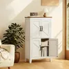 A white storage cabinet with a brown top sits in a well-lit room next to a plant and a sofa. Produktbild-Vorschau
