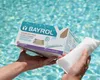 Hands holding a box of BAYROL Superflock Plus pool treatment product over a swimming pool. Anteprima dell’immagine prodotto