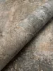 A close-up view of a rolled-up wallpaper with a concrete texture. Produktbild-Vorschau