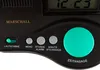A close-up of a black digital alarm clock with several buttons and a large green dial. Produktbild-Vorschau