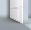 A close-up view of a white wall paneling with vertical grooves, set against a light gray floor and a light blue wall. Podgląd zdjęcia produktu
