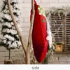 A Christmas stocking hanging from a tree branch, with a snowy tree and brick wall in the background. Náhľad obrázku produktu