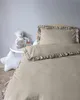A baby bed with bedding and a teddy bear on a side table. Produktbild-Vorschau