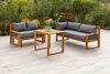 An outdoor patio setting with a wooden lounge set and flowers in the background. Produktbild-Vorschau
