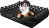 A dog is lying on a black dog bed with white paw prints. Náhled obrázku produktu