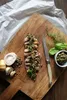 A sliced steak dish with a side of sauce, herbs, garlic, and spices on a wooden cutting board. Voir les images du produit