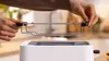 A person's hands are holding a toaster rack above a white toaster. Produktbild-Vorschau