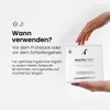 A hand is holding a product box with text and graphics on it, against a plain background. Produktbild-Vorschau