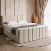 A bedroom scene featuring a beige upholstered boxspring bed with a decorative headboard.
