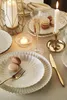 A beautifully set table with dinnerware, candles, and macarons, suggesting a festive or special occasion. Produktbild-Vorschau