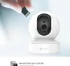 A hand is inserting a microSD card into a white security camera. Voir les images du produit