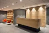 A reception area with a wooden reception desk, shelving, and chairs. Anteprima dell’immagine prodotto