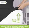 A hand is stretching a black fitted sheet over a white mattress. There is a green arrow and text indicating mattress height. Produktbild-Vorschau