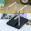 A Newton's cradle on a wooden desk, placed on top of some papers. Produktbild-Vorschau