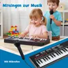 Two young children are playing with a keyboard and microphone in a room. Náhled obrázku produktu