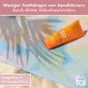 A sunscreen tube is placed on a colorful beach towel with palm leaf shadows. Sand is visible in the foreground. Podgląd zdjęcia produktu