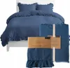 A blue duvet cover and pillowcases with ruffles are displayed on a white bed, with packaged pillowcases in the foreground. Anteprima dell’immagine prodotto