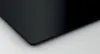 A close-up of the corner of a black induction hob. Voir les images du produit