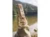 A wooden mechanical model of a hurdy-gurdy is displayed on a rock near a lake. Produktbild-Vorschau