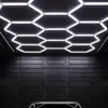 A modern workshop or garage with hexagonal LED ceiling lights illuminating a dark, textured wall and the top of a vehicle. Náhled obrázku produktu