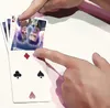Hands holding playing cards, with a close-up of two faces on one of the cards. Produktbild-Vorschau