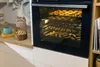 A modern kitchen scene with an oven filled with baked goods. Produktbild-Vorschau