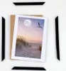 A set of black picture frames arranged around a photo of a beach scene. Produktbild-Vorschau