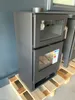 A black wood-burning stove with a glass door and an oven compartment, placed on a wooden pallet. Anteprima dell’immagine prodotto