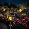 A garden at night, illuminated by solar-powered decorative lights shaped like moons with fairies and lanterns. Produktbild-Vorschau