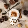 A close-up overhead view of a festive assortment of chocolates, cookies, and a drink, dusted with cinnamon. Náhled obrázku produktu