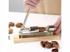 A person is using a metal nutcracker to crack a nut, with other nuts and cracked shells around it. Náhled obrázku produktu