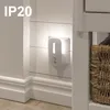 A white night light is plugged into a white shiplap wall, next to a wicker basket. Podgląd zdjęcia produktu