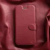 A dark red leather phone case is laid flat on a wrinkled, dark red leather surface. Produktbild-Vorschau