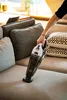 A person is using a handheld vacuum cleaner on a sofa. Anteprima dell’immagine prodotto