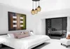 A bedroom with a large bed, a painting on the wall, and a modern pendant light fixture. Produktbild-Vorschau