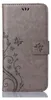 A grey flip phone case with a floral and butterfly embossed pattern. Produktbild-Vorschau
