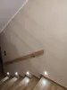A staircase with wooden steps and a wooden handrail, illuminated by small square lights embedded in the wall. Náhľad obrázku produktu